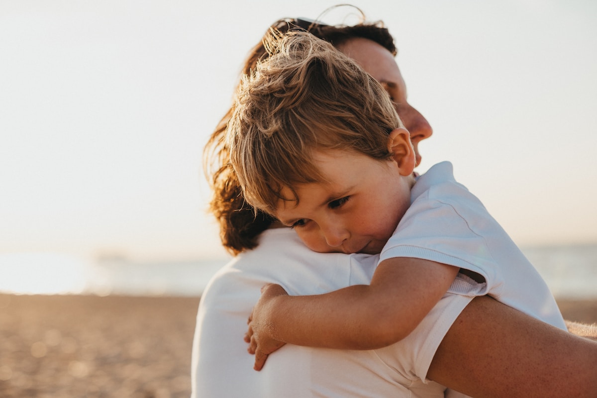 Un parent serre son enfant dans ses bras, dans la lumière du soir